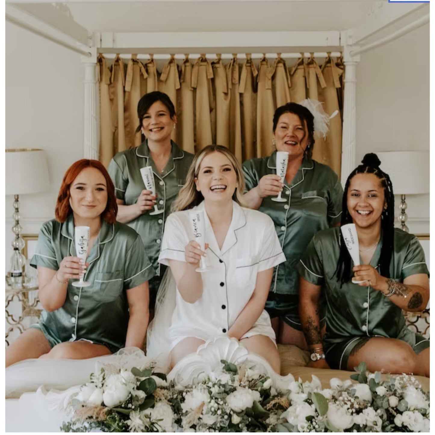 Group of women in matching pajamas with a floral arrangement on a bed.