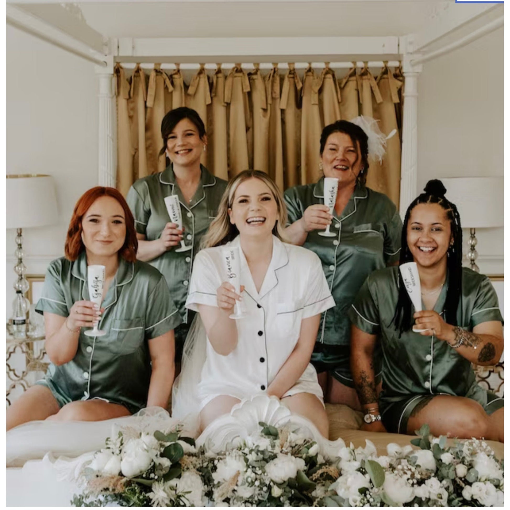 Group of women in matching pajamas with a floral arrangement on a bed.